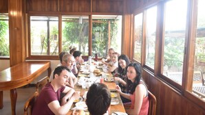 A wooden dining area with large windows, a ceiling fan, and a table set for a meal. - Hotel San Vicente Galapagos (Puerto Villamil)