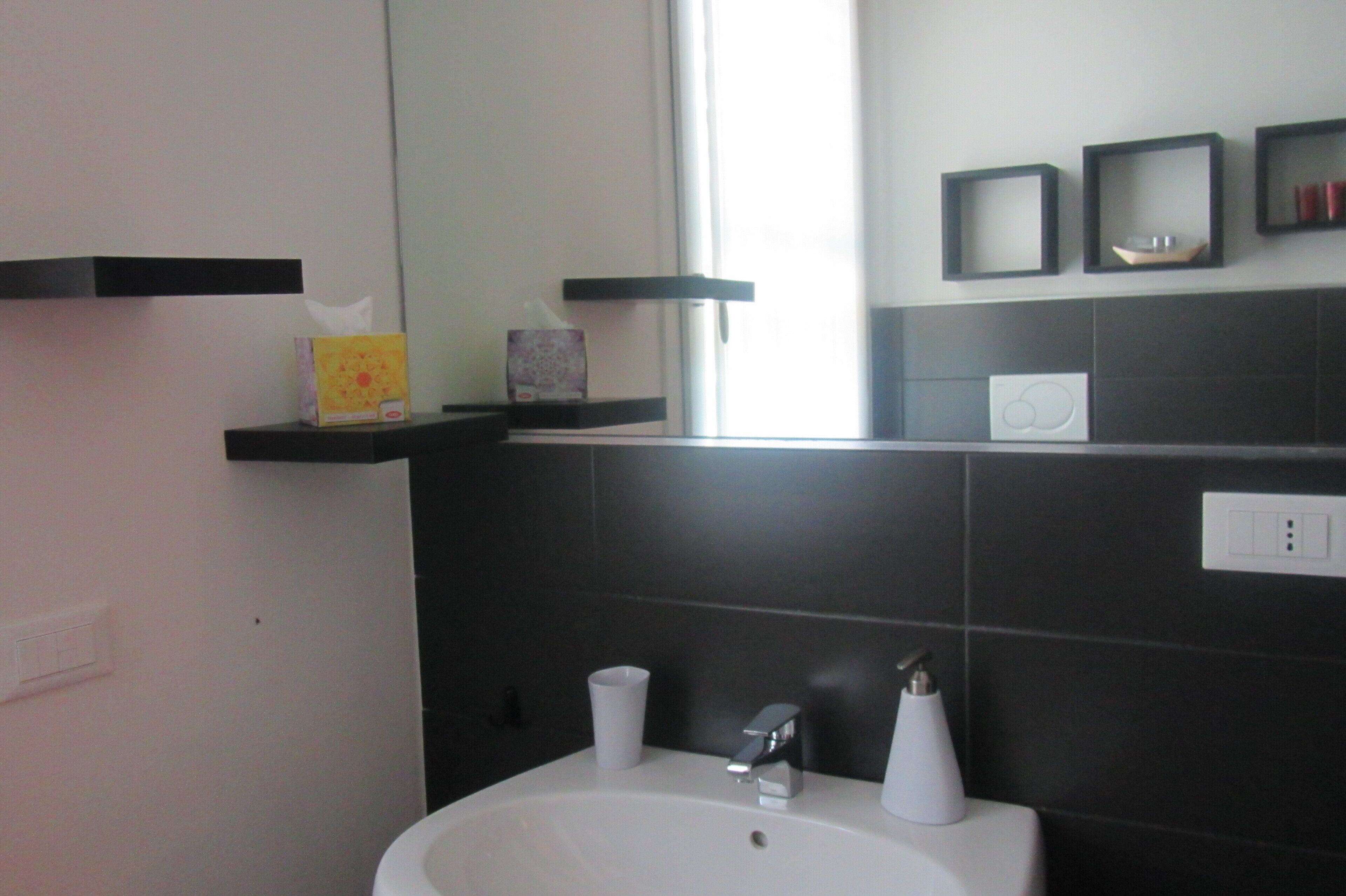 A bathroom with a white sink, two faucets, a mirror, and a window.