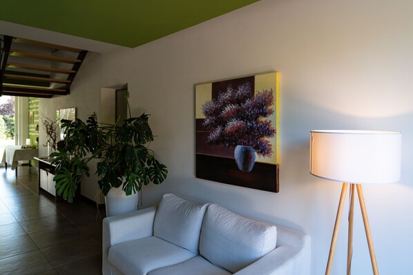 A modern living room with a white sofa, a floor lamp, and a painting on the wall.