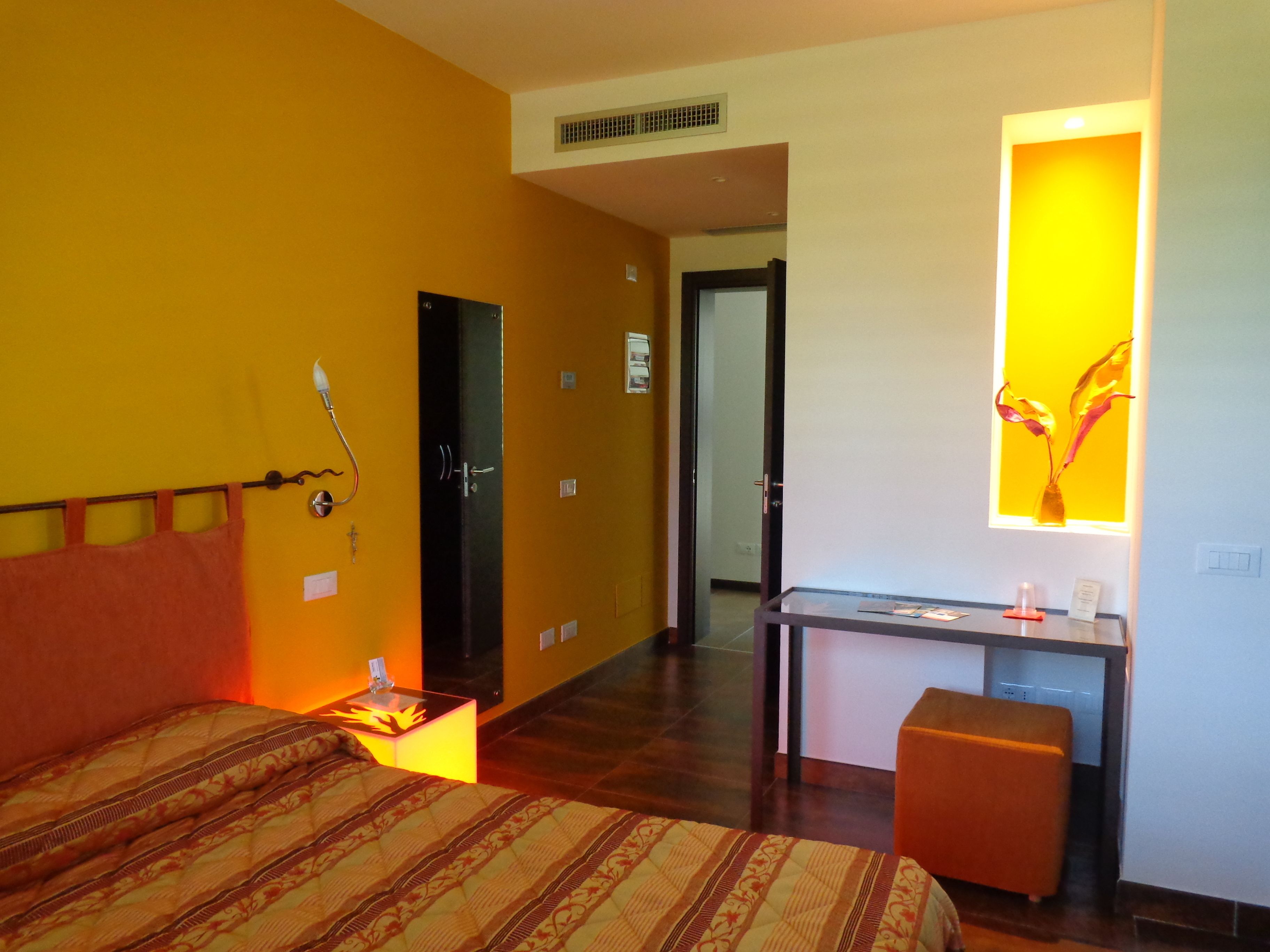 Habitació d'hotel amb llit, taula de nit, escriptori i mirall.