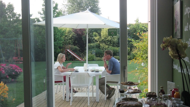 Ein Wintergarten mit Glasveranda, einem weißen Tisch und Blick auf einen Garten.