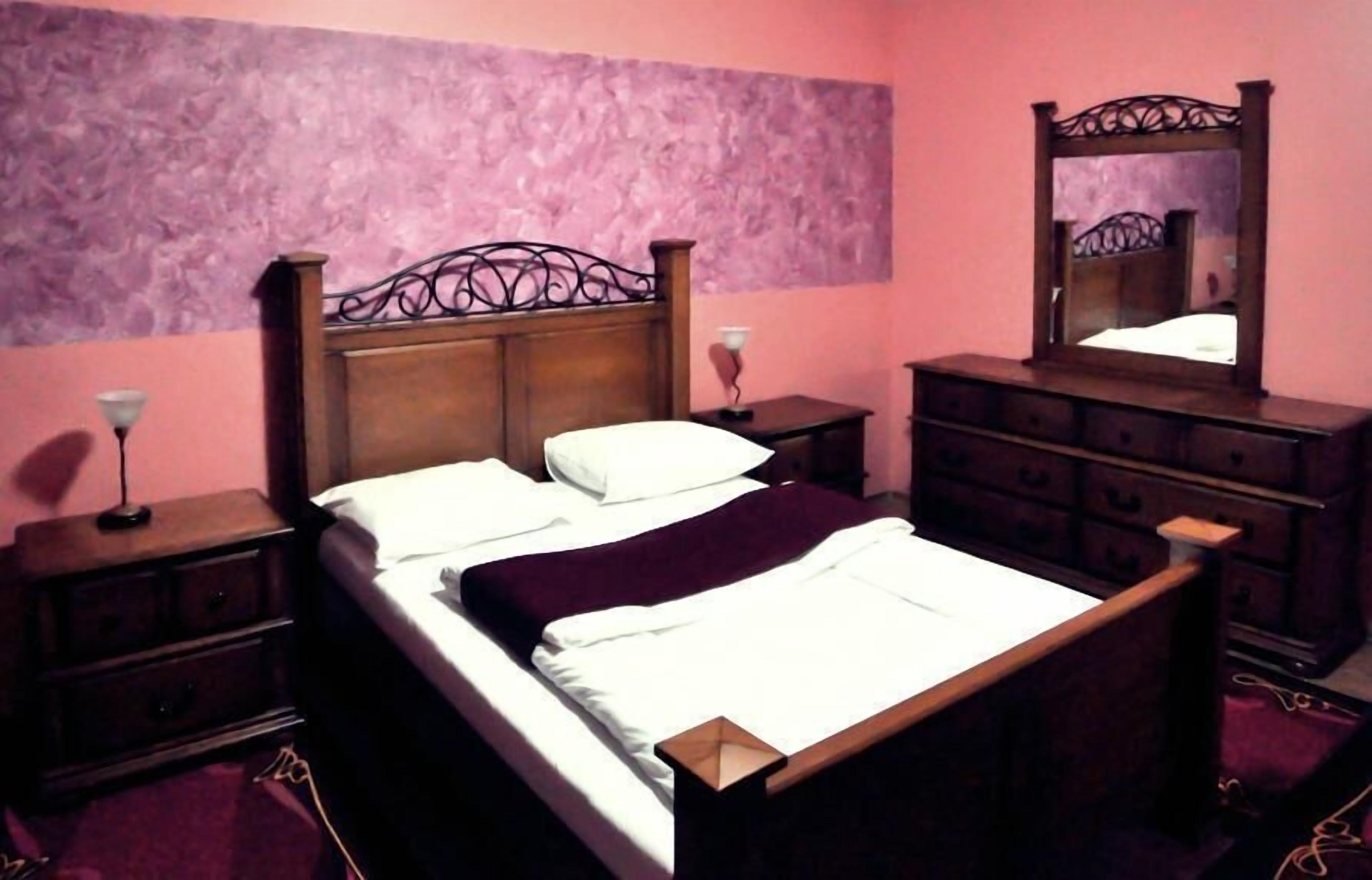 Une chambre à coucher avec un lit en bois, une table de chevet, une commode et un miroir.