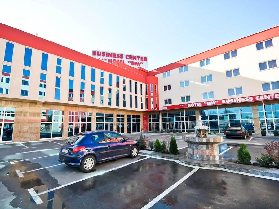 Een hotel met een bedrijfszaal, met een parkeerplaats en een fontein.