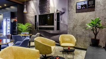 A modern lounge area with comfortable seating, a television, and a large wall mural.