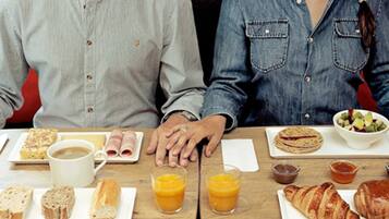 A dining table with breakfast items including croissants, bread, juice, and a coffee cup.