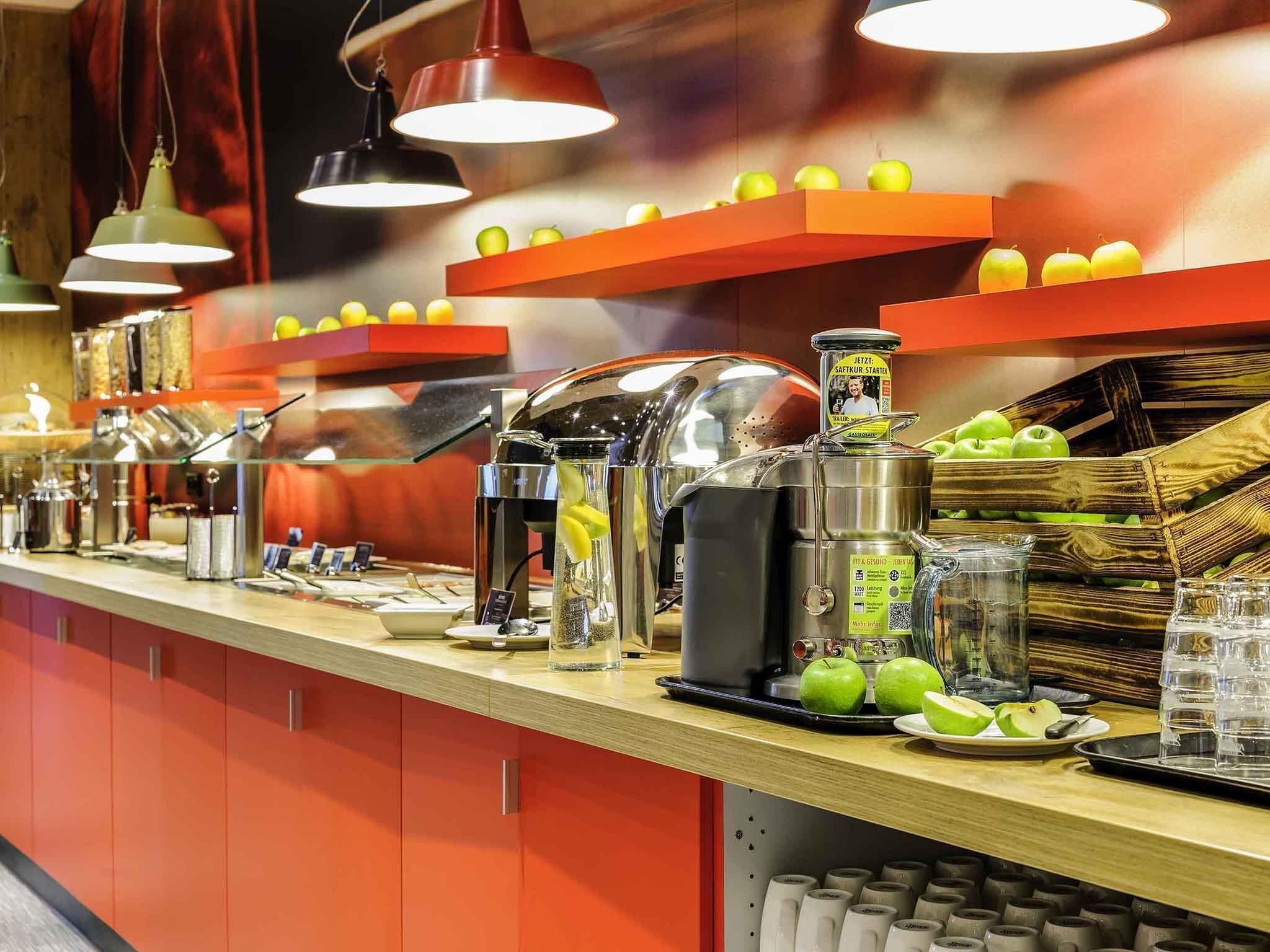 Un mostrador de buffet con diferentes opciones de comida, una máquina de café y un dispensador de zumo.