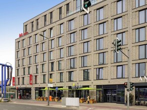 A multi-story hotel with a uniform facade, a bike parking area, and a nearby restaurant. - ibis Berlin Hauptbahnhof (Berlin)
