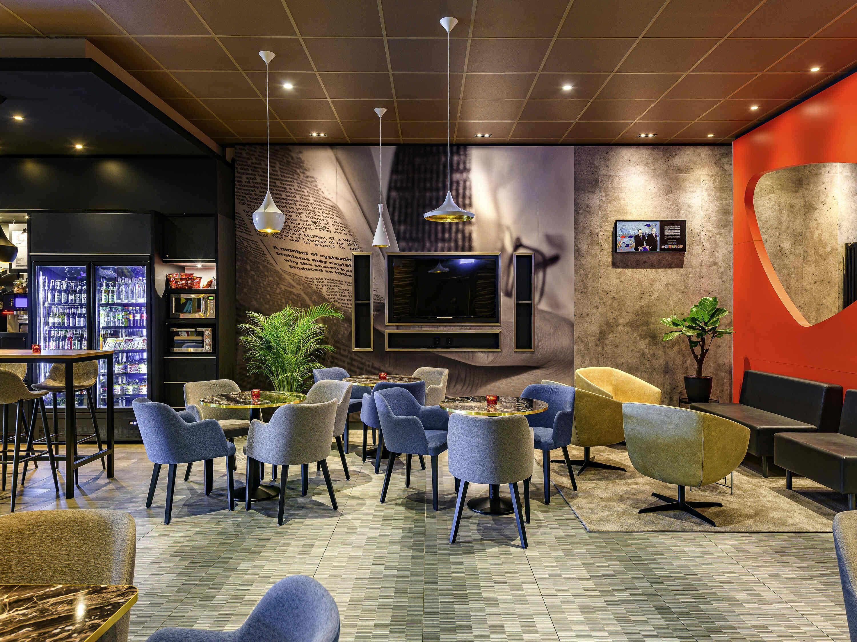 A modern lounge area with seating, a bar, and a television.