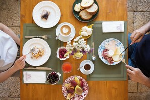 Una mesa de madera con diversos productos de desayuno, como pasteles, frutas y bebidas.