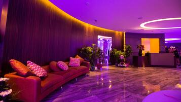 A reception area with a curved red sofa, a reception desk, and potted plants.
