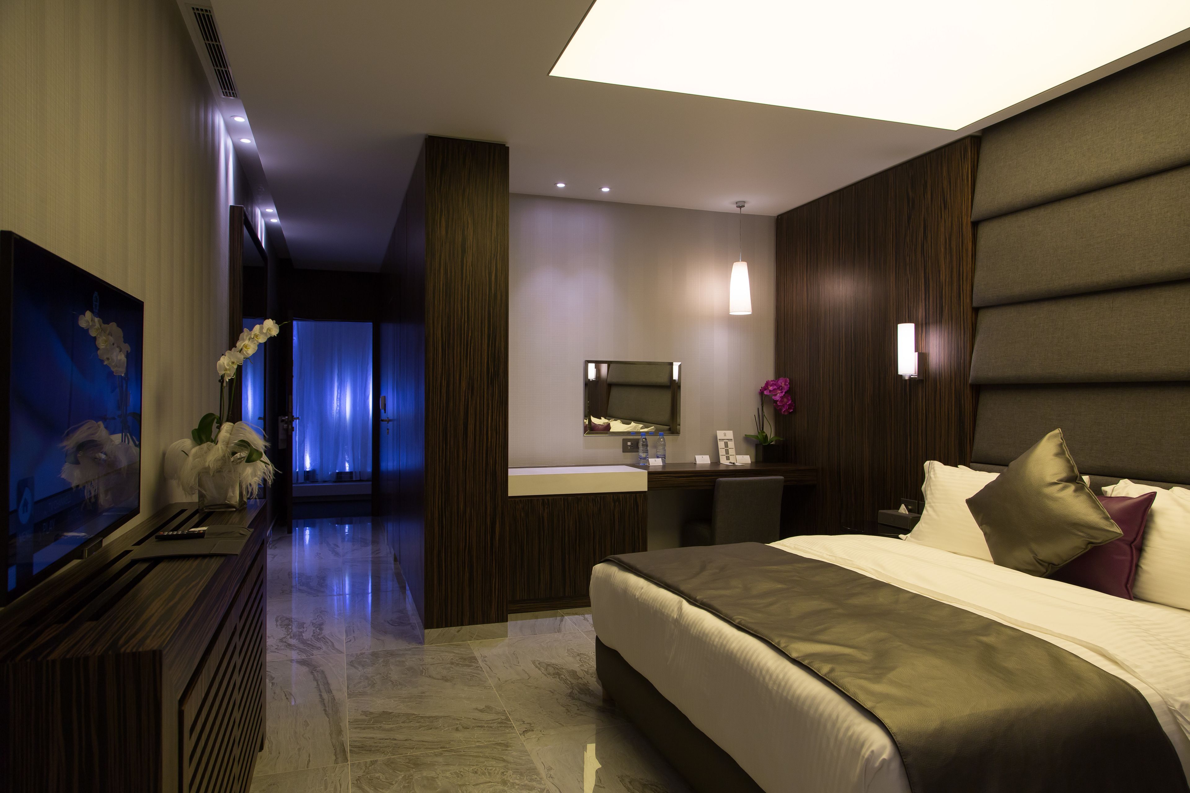 Een moderne hotelkamer met een groot bed, een bureau, een spiegel en een televisie.