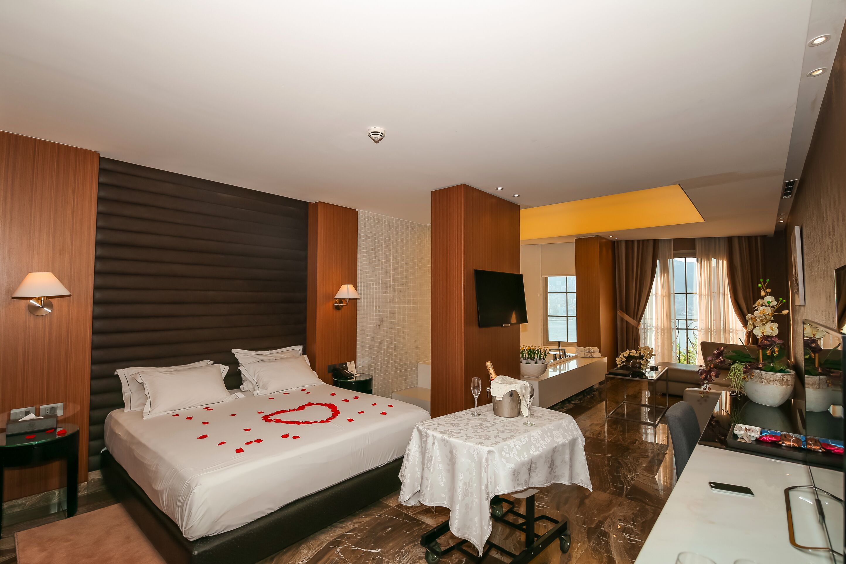 Une chambre d’hôtel avec deux lits, un bureau, une chaise, une télévision et une salle de bain visible au fond.