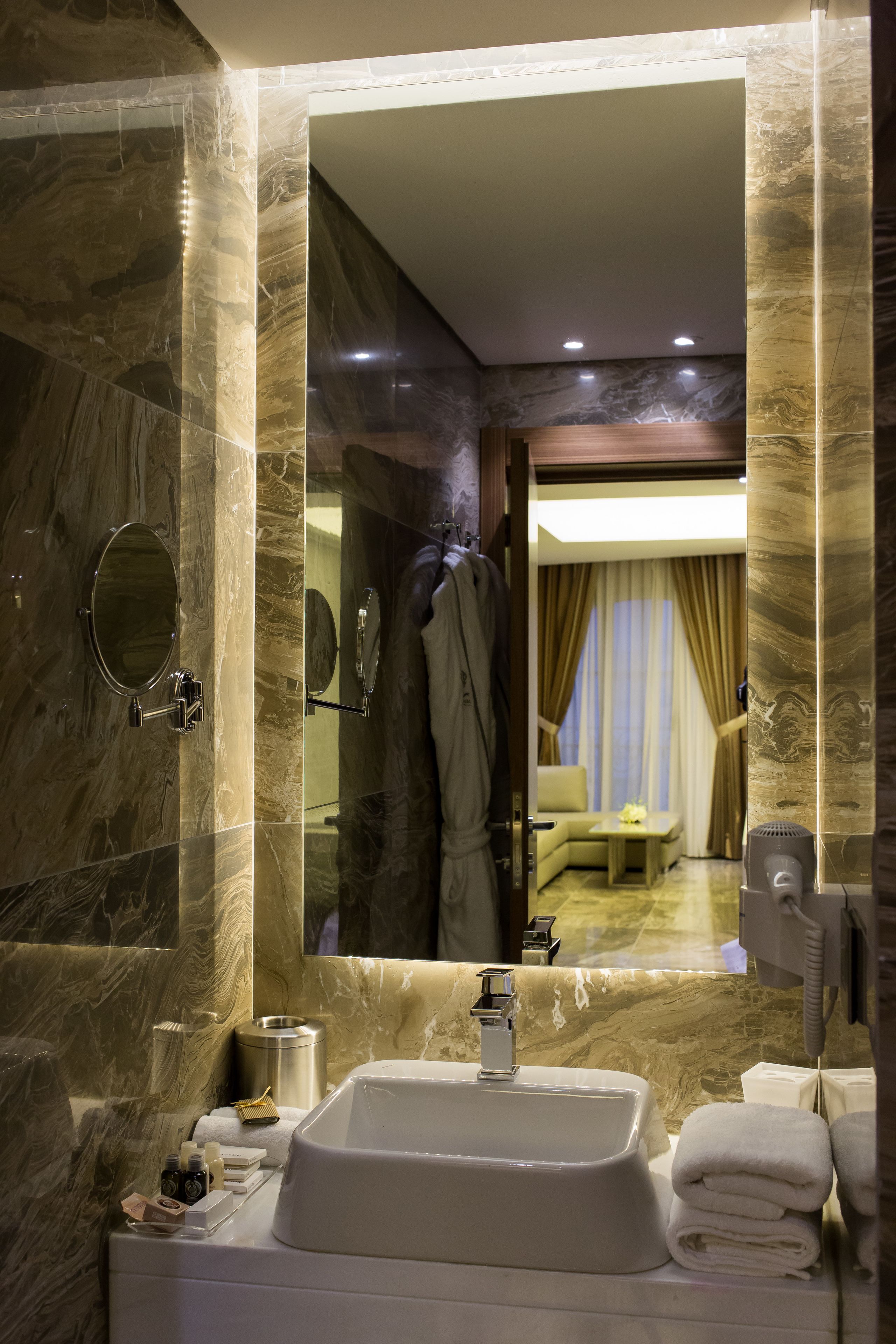 A modern bathroom with a marble sink, a mirror, and a shower area.
