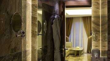A modern bathroom with a marble sink, a mirror, and a shower area.