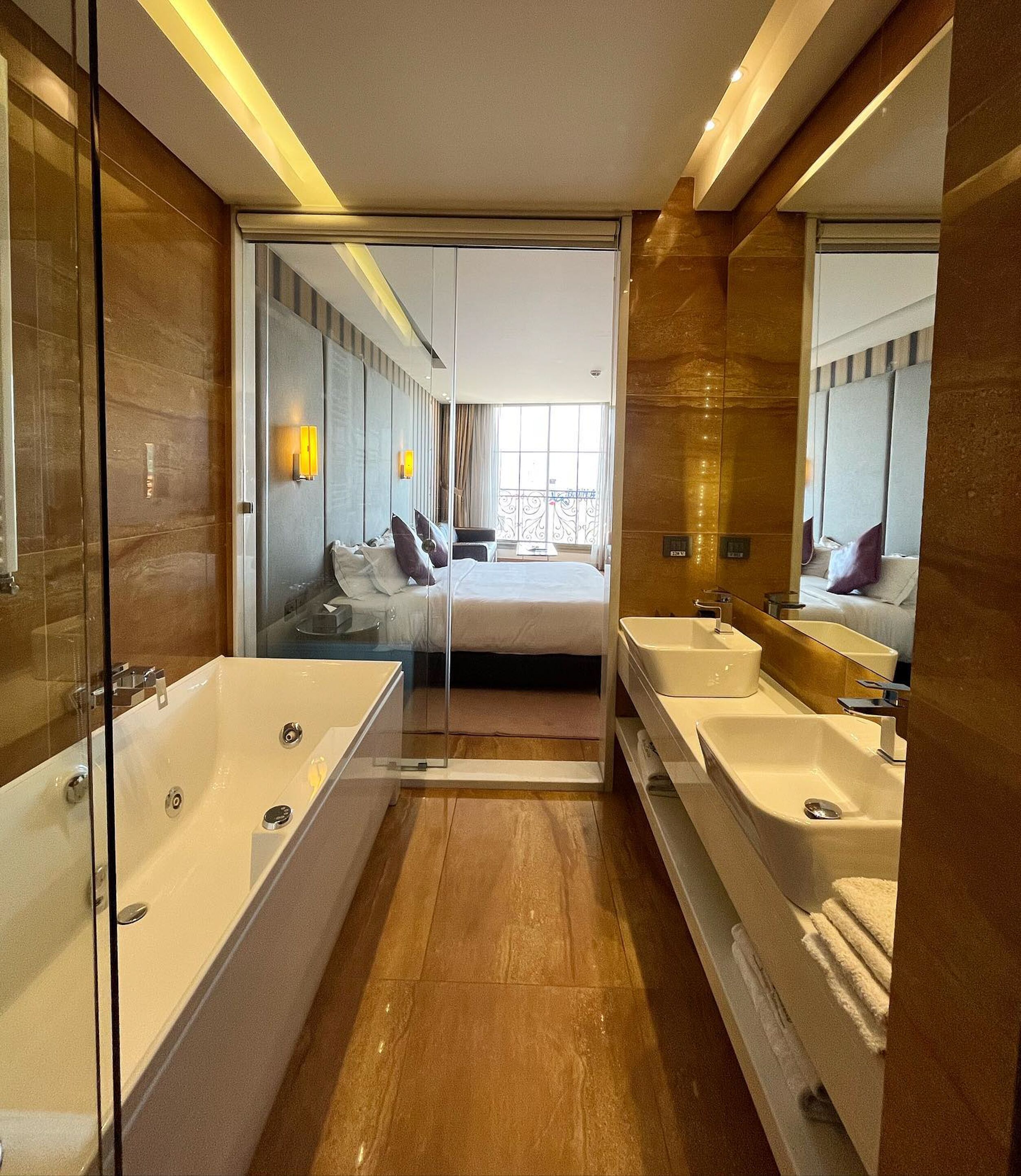 Ein modernes Badezimmer mit einer gläsernen Dusche, zwei Waschbecken und einem großen Spiegel.