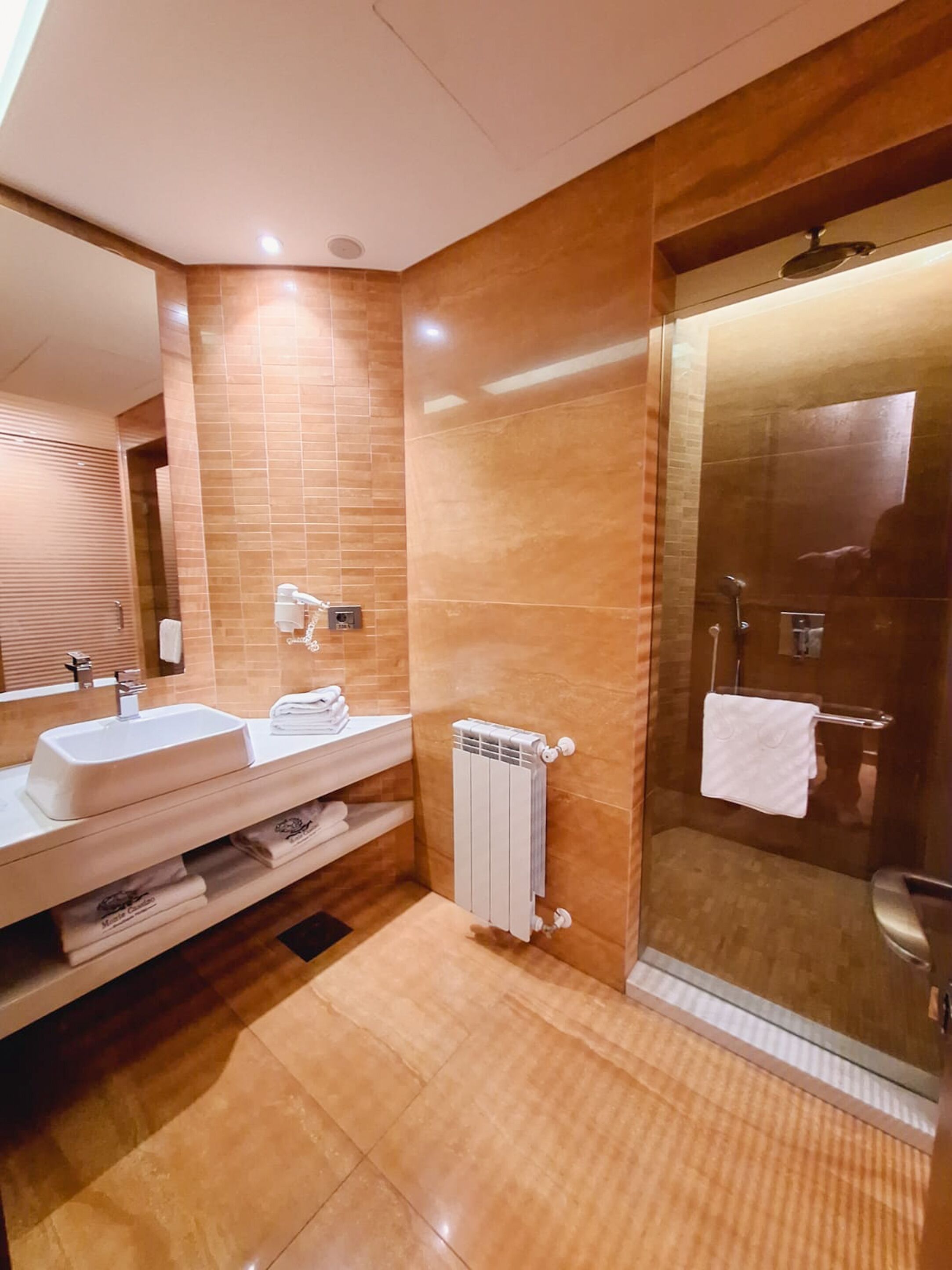 Een moderne badkamer met twee wastafels, een douchecabine van glas en een zichtbare handdoekhouder.