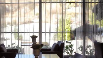 A room with large windows, a table, chairs, and a hanging light fixture.