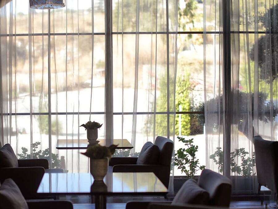 A room with large windows, a table, chairs, and a hanging light fixture.