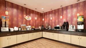Un bar pour prendre le petit-déjeuner, avec un mur décoré de motifs, une machine à café et une bouilloire.