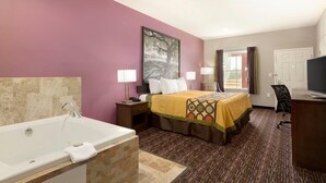 Une chambre d’hôtel avec un grand lit, une baignoire, un bureau et un téléviseur.