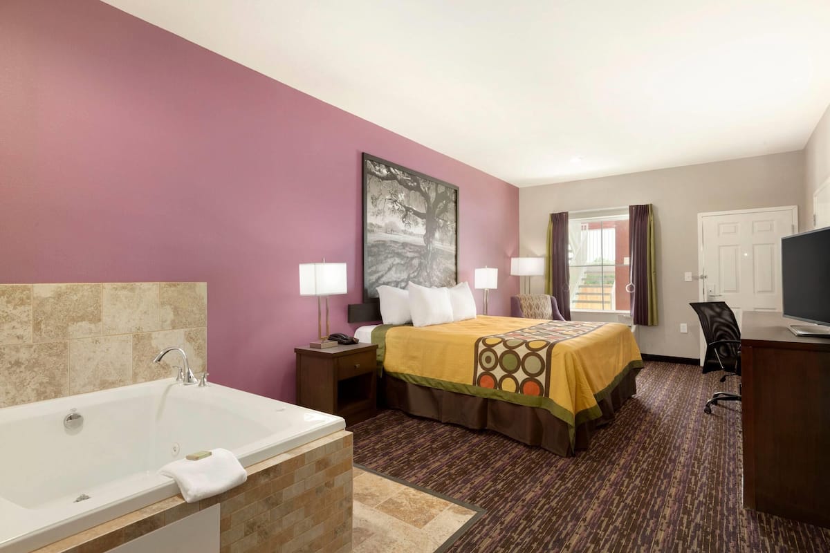 Une chambre d’hôtel avec un grand lit, une baignoire, un bureau et un téléviseur.