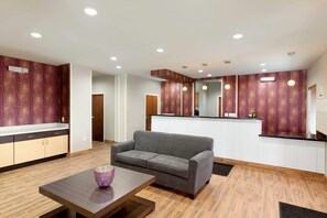 Een modern interieur met een grijze bank, houten vloeren en een keuken met een backsplash met een rood patroon.
