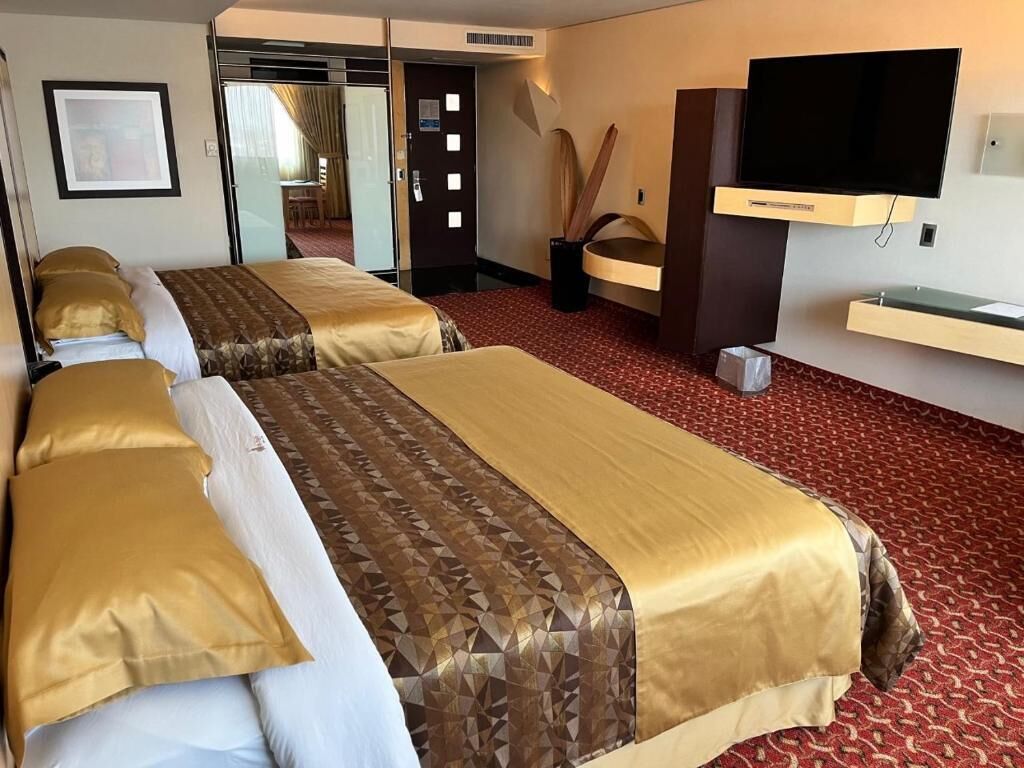 A hotel room with two beds, a television, and a bathroom.