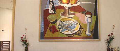 A large abstract painting on a wall above a bar area with a wooden counter and wine bottles.