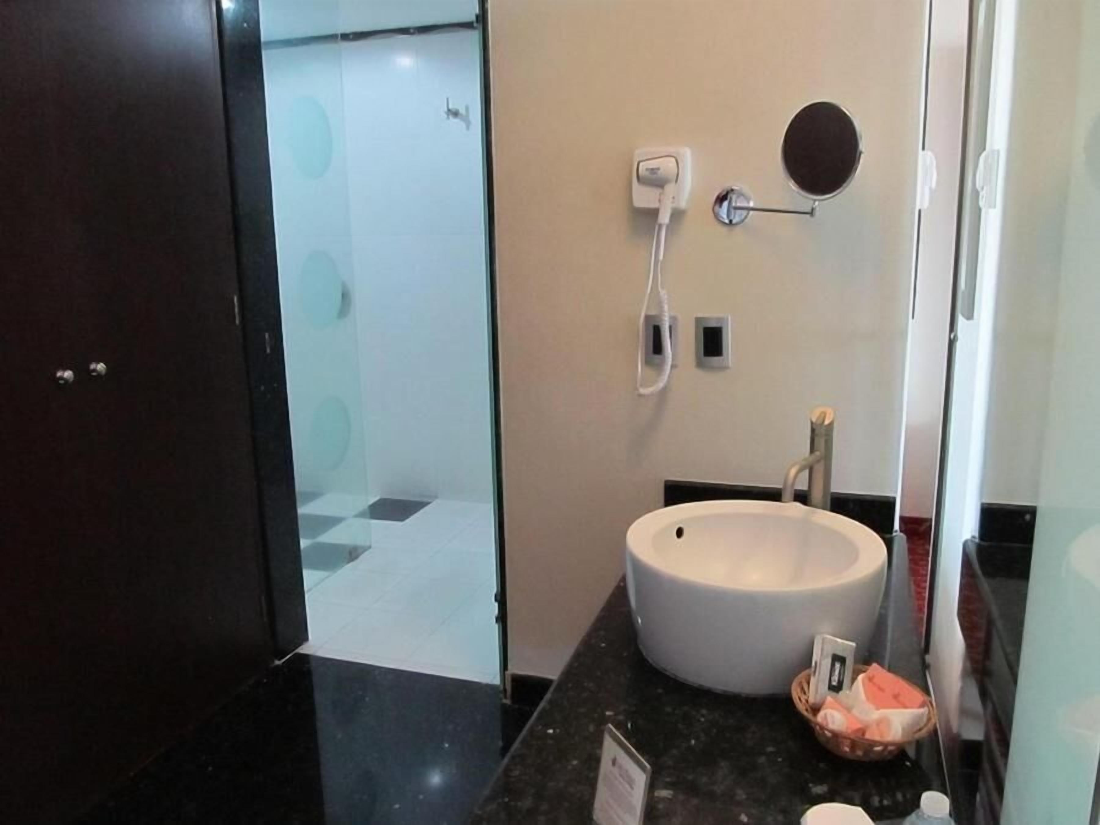 Ein modernes Badezimmer mit einem großen Waschbecken, einem Spiegel und einem Handtuchhalter.