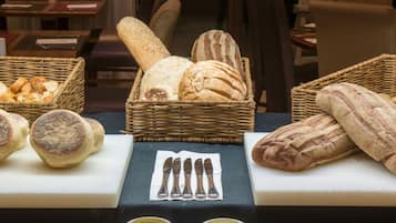 A display of various breads and pastries on a table, accompanied by cutlery and a napkin.