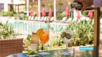 A bar area with a pool view, featuring three drinks on a table.