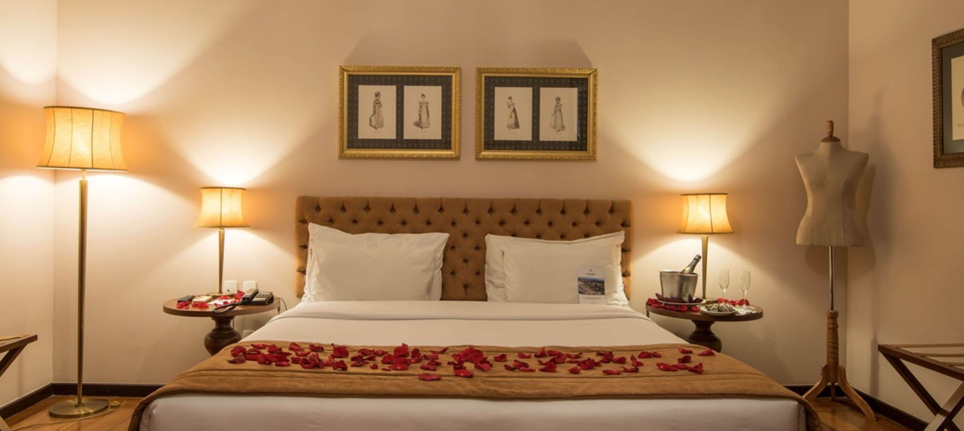 A hotel room with a large bed, two bedside tables, a headboard, and two framed pictures on the wall.