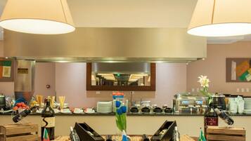 Una cocina de hotel con una campana extractora de acero inoxidable, un espejo grande sobre la encimera, y diversos utensilios y electrodomésticos.