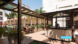 Un bar junto a la piscina con asientos exteriores y vistas al área de la piscina.