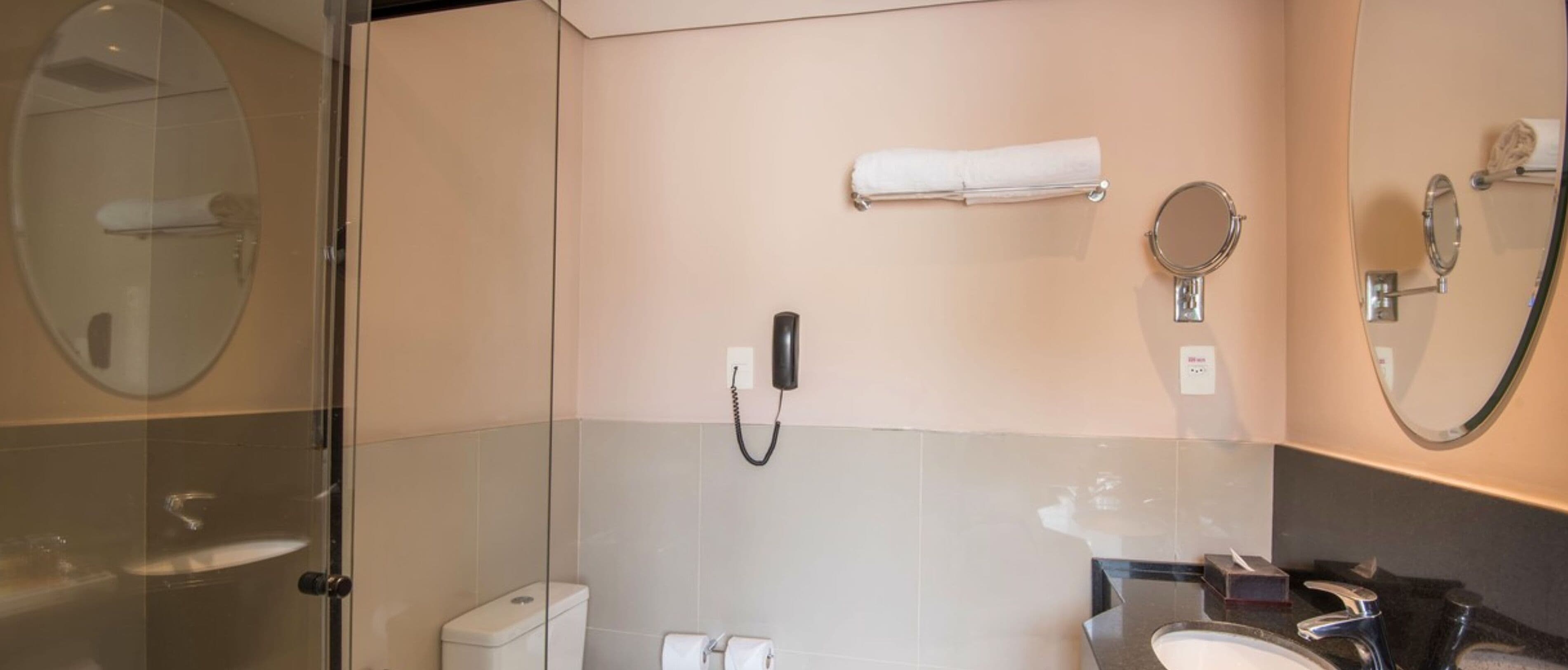 Un baño moderno con cabina de ducha de vidrio, inodoro, lavabo y espejo.