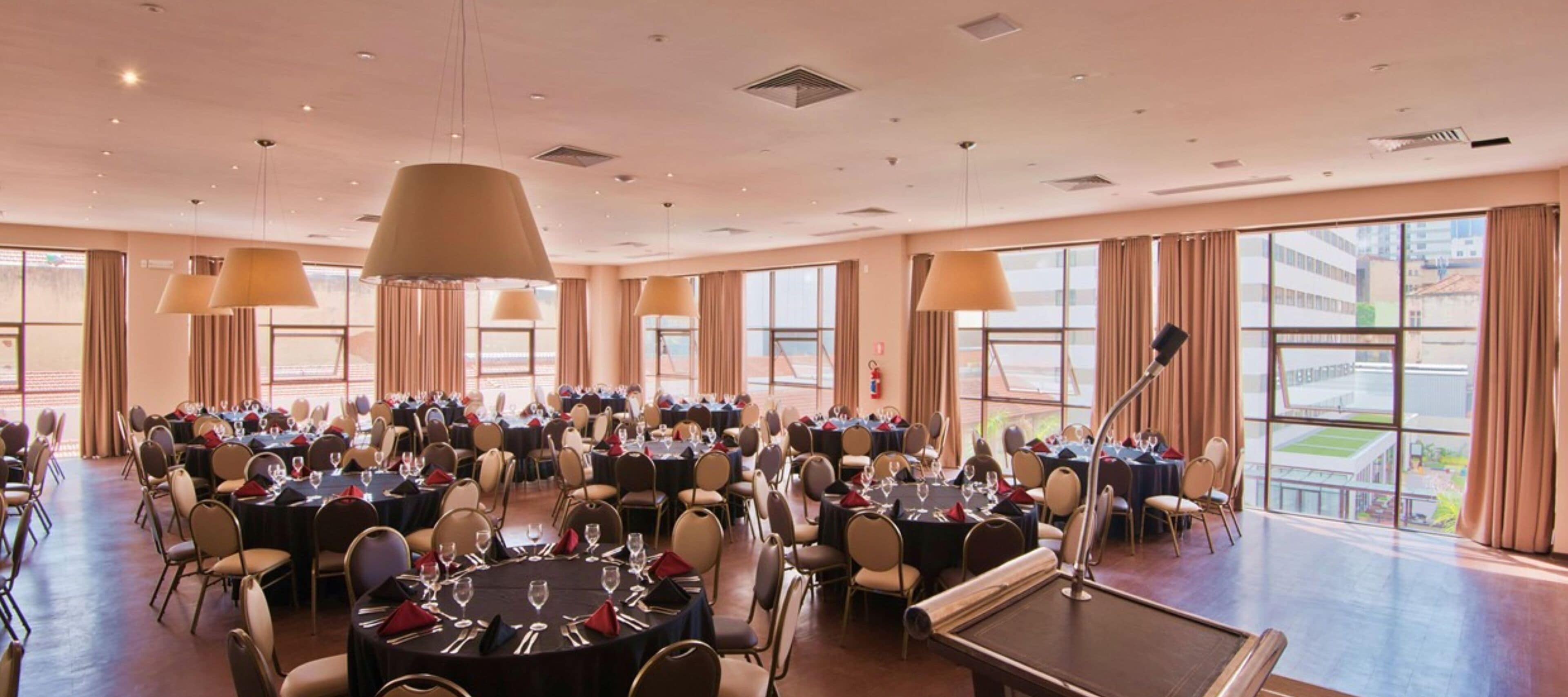 A large conference room with round tables, chairs, and a podium.