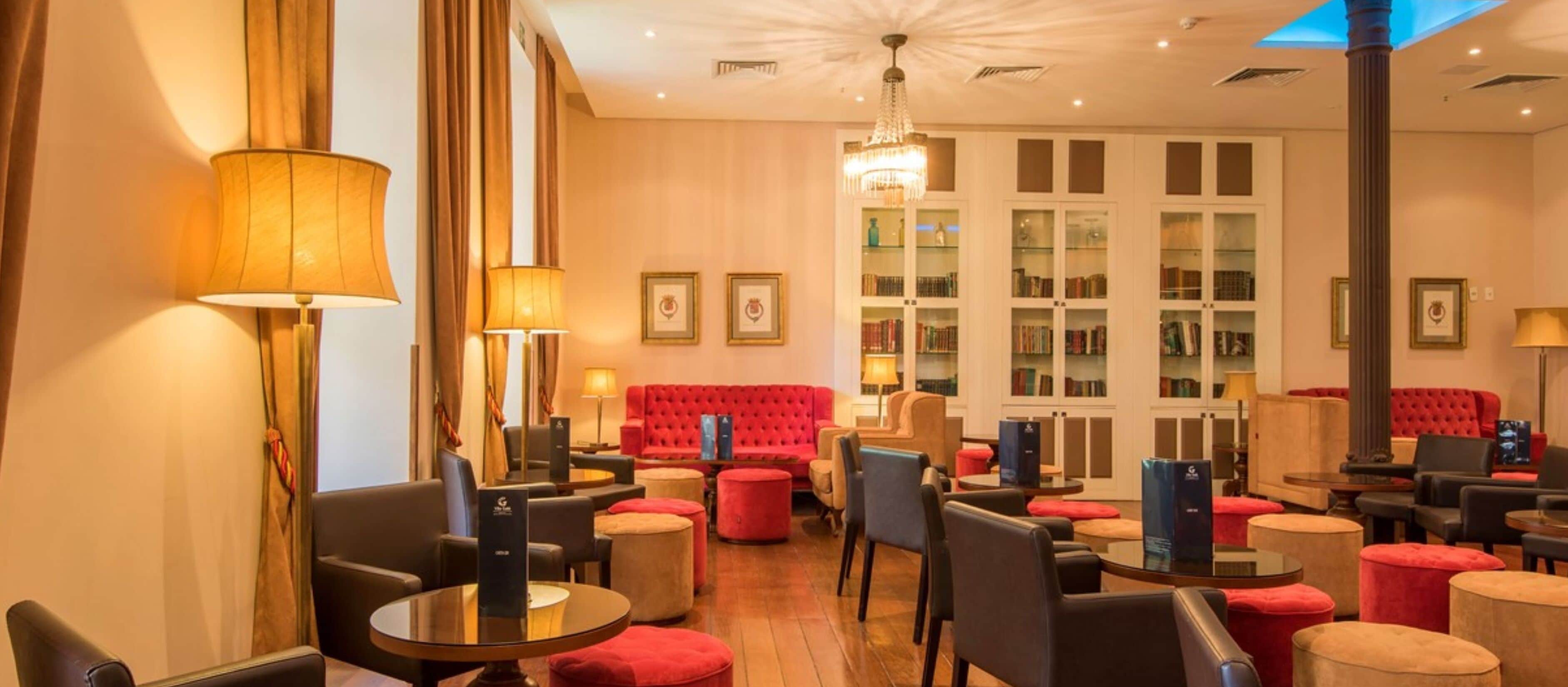 A hotel lobby with a red sofa, multiple seating areas, and a chandelier.