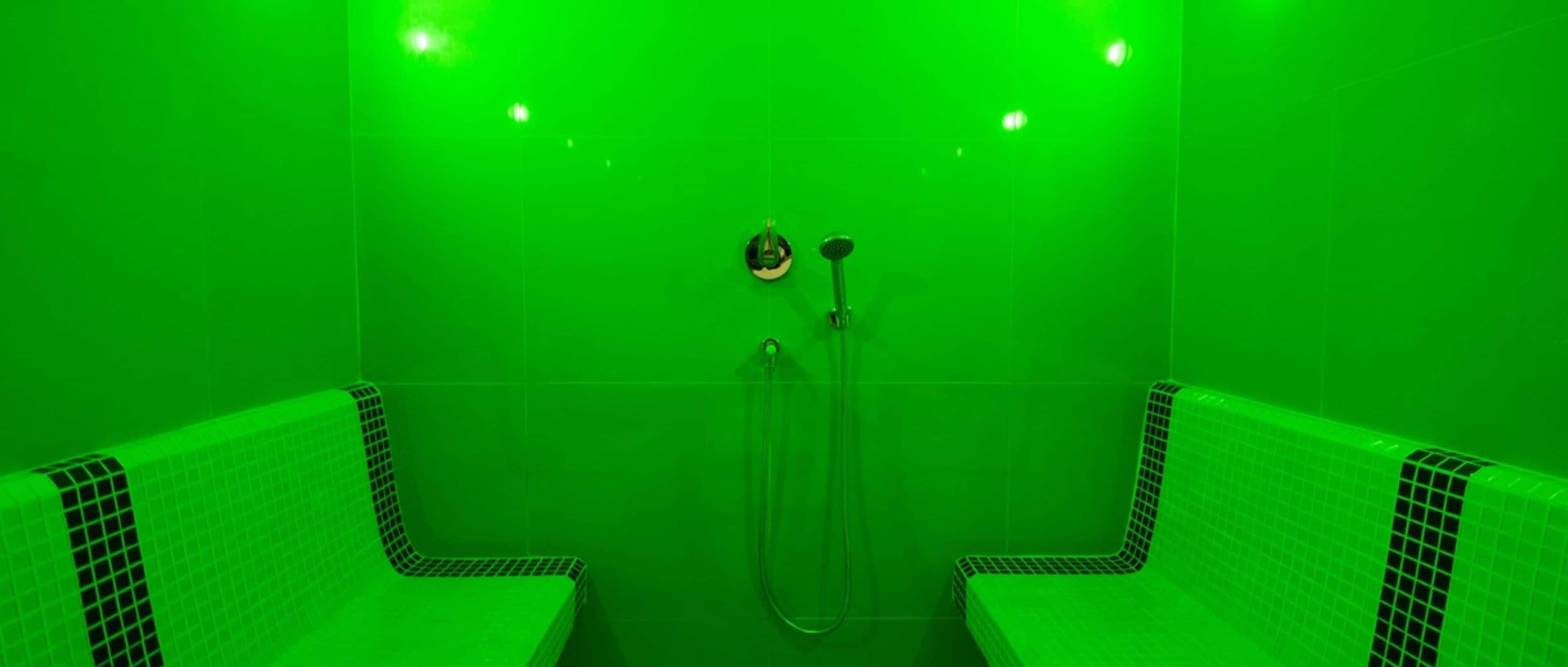 A bathroom with green-tiled walls and a shower area.