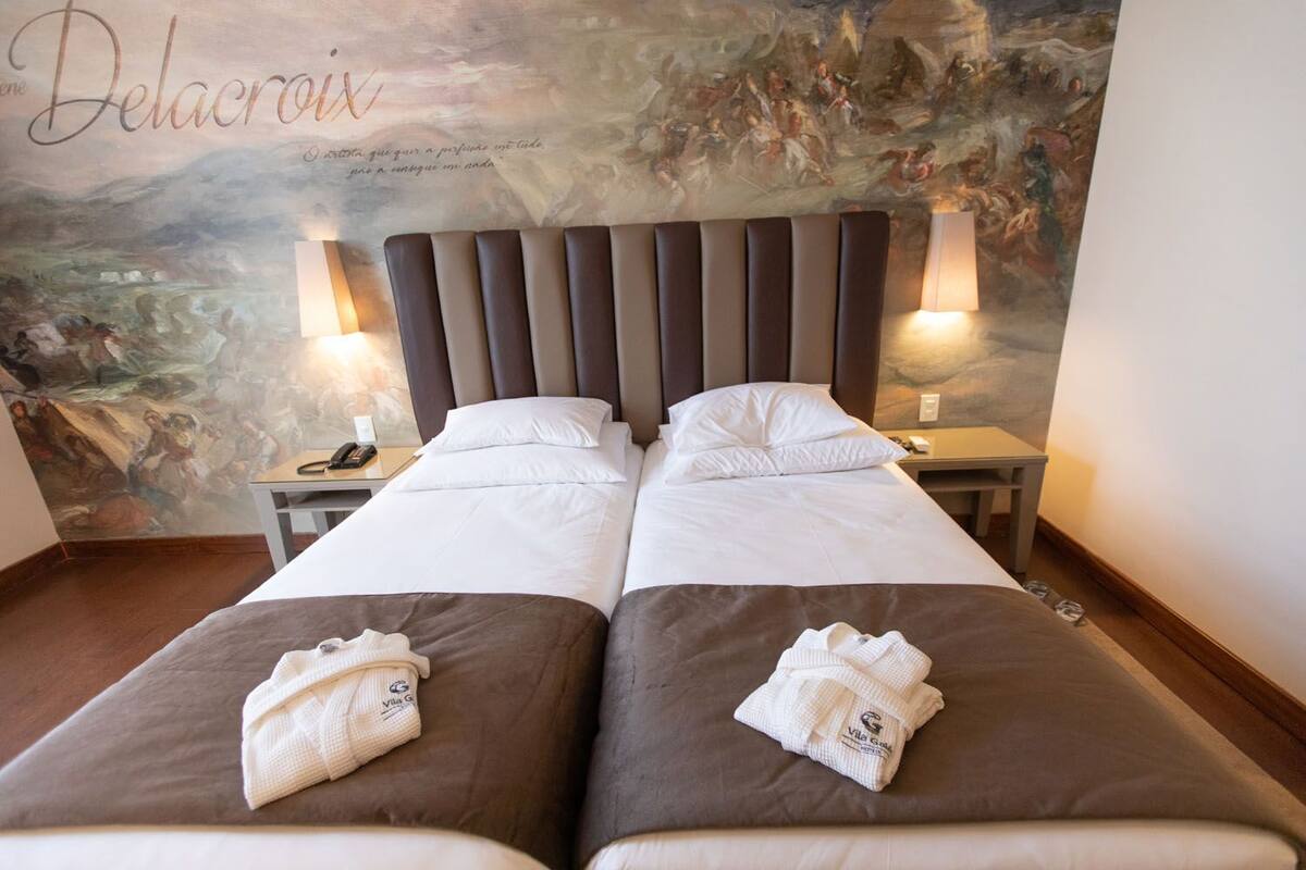A double bed with a headboard, two bedside tables, and a mural on the wall.