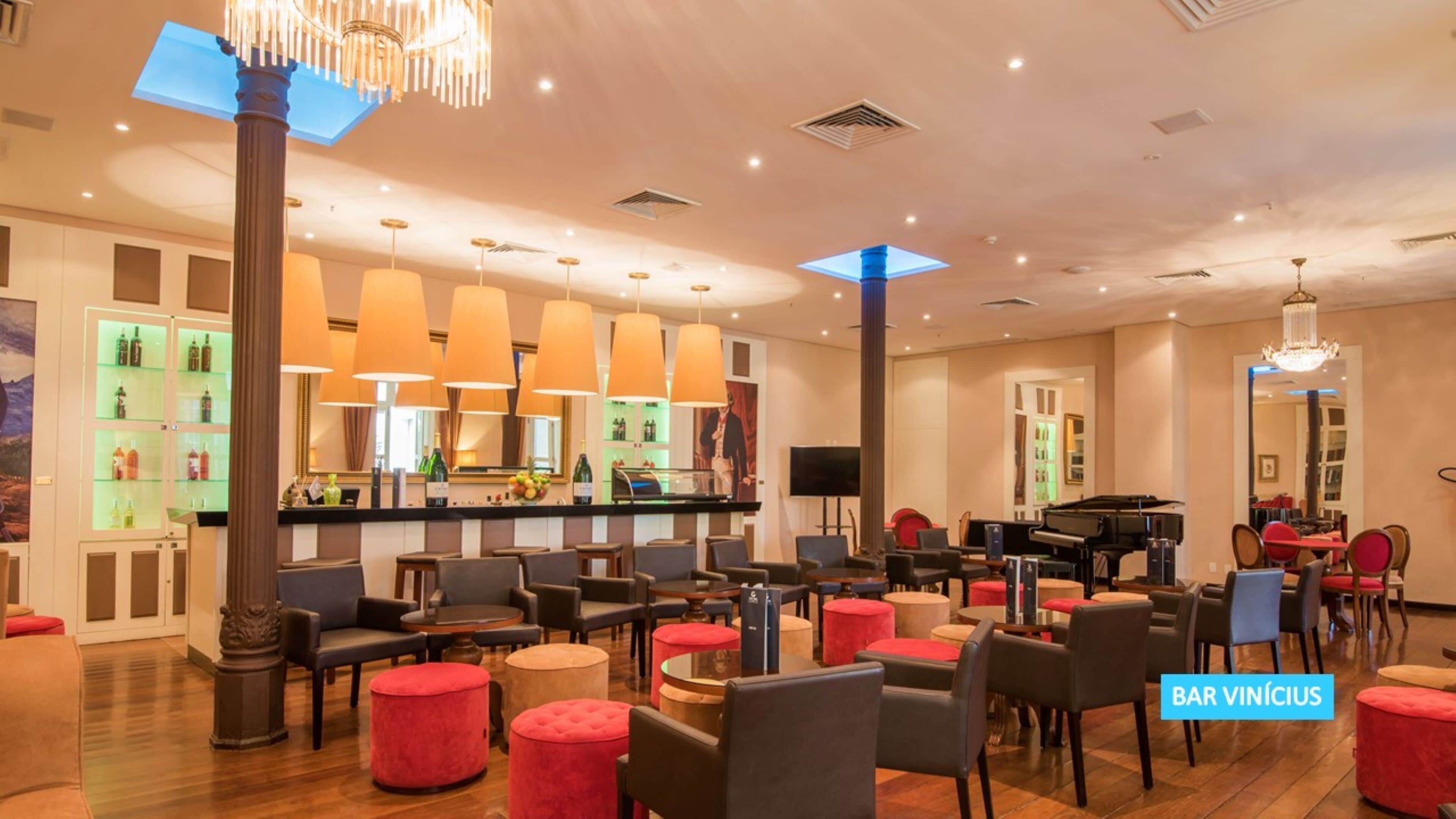A spacious lobby with a bar area, seating arrangements, and a grand piano.