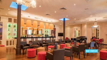 A spacious lobby with a bar area, seating arrangements, and a grand piano.
