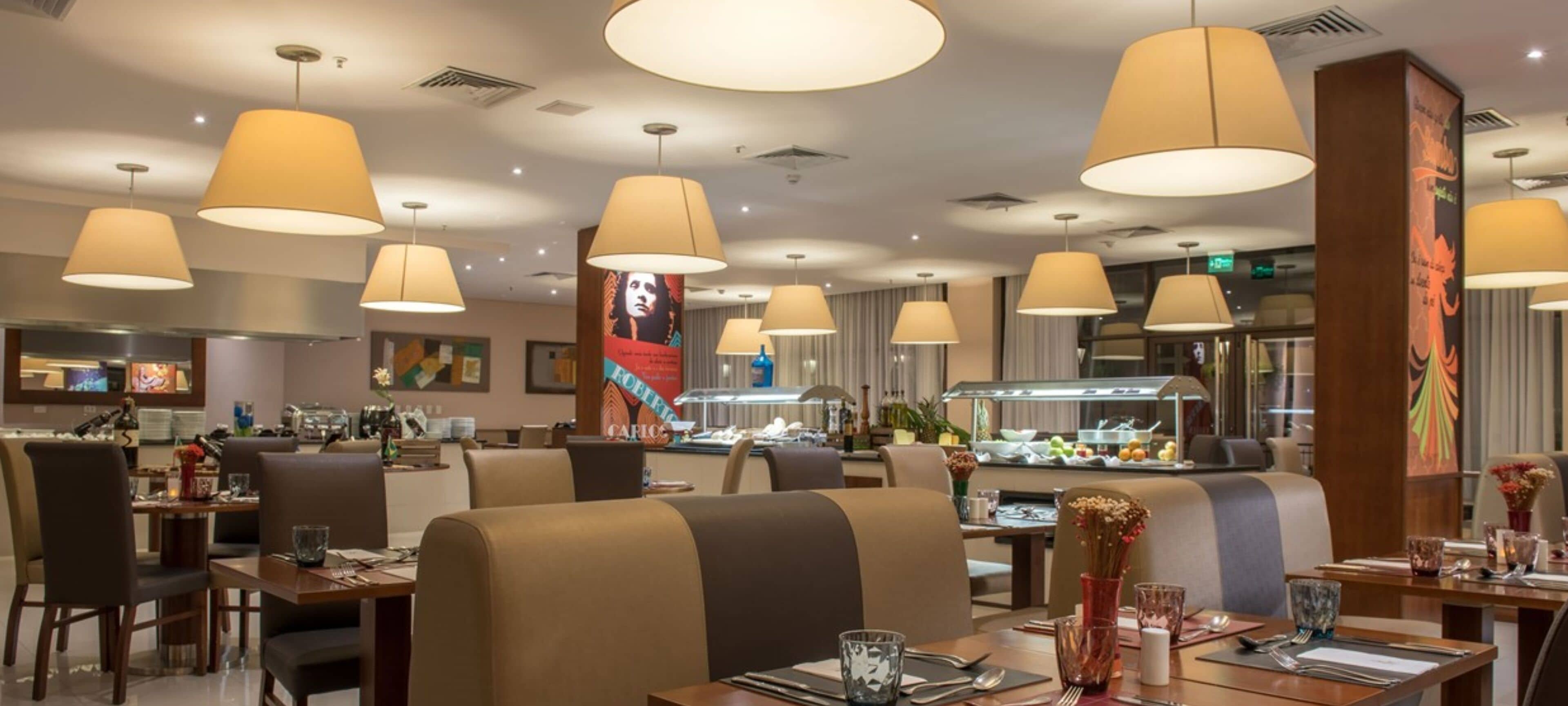 Restaurante moderno com mesas altas, assentos confortáveis e iluminação pendente.