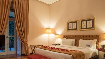 A hotel room with a large bed, two bedside lamps, a flat-screen TV, and a large window with curtains.