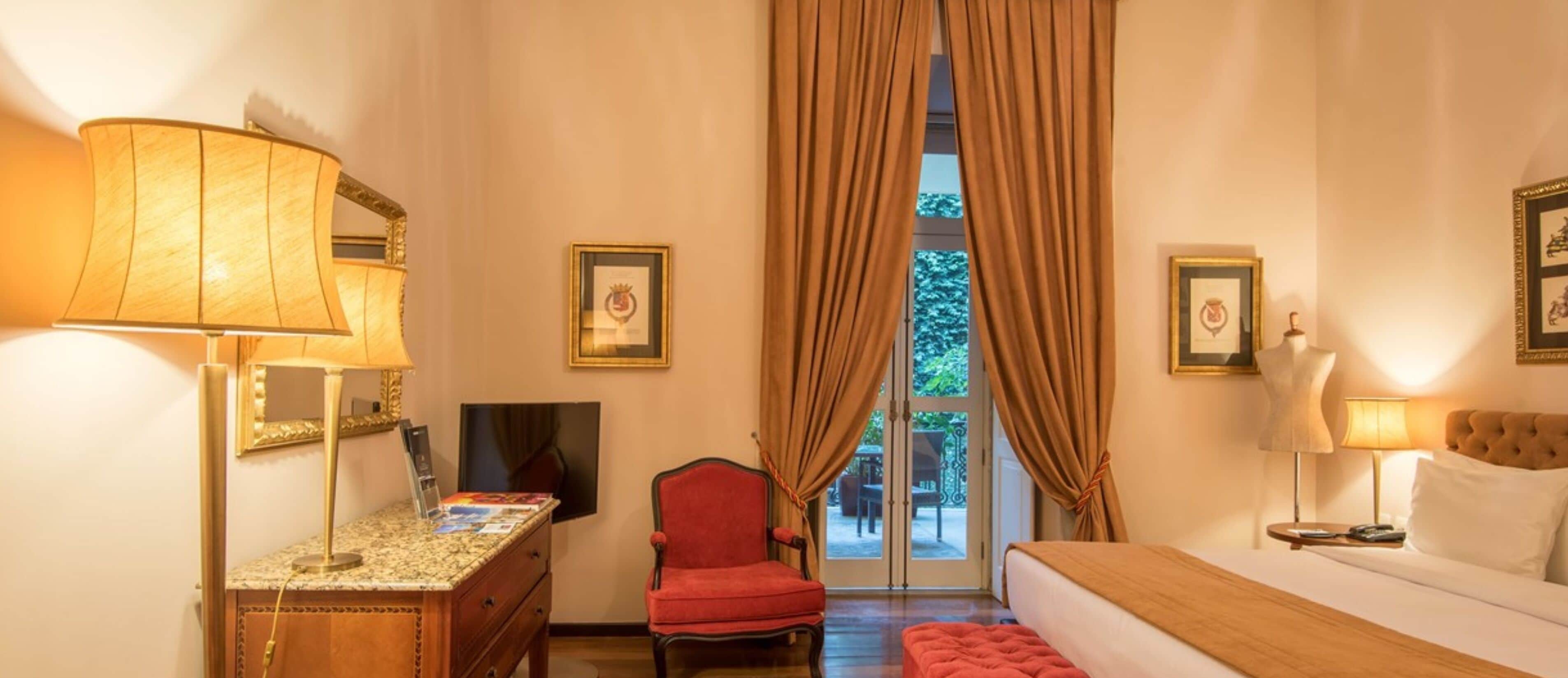 Una habitación de hotel con cama, escritorio con lámpara, silla y televisión.