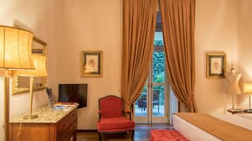A hotel room with a bed, a desk with a lamp, a chair, and a television.