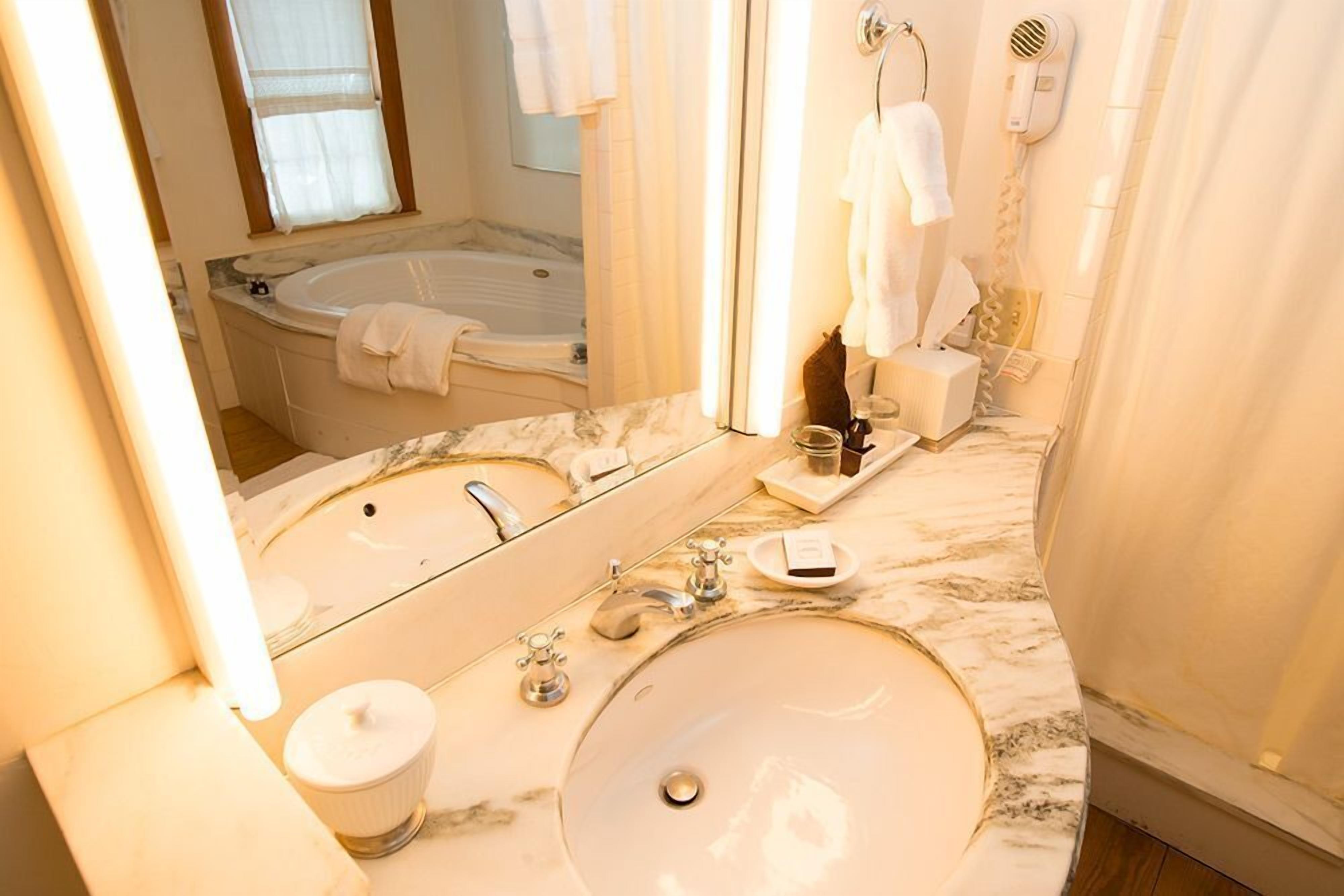 A bathroom with a large sink, a bathtub, and a mirror.