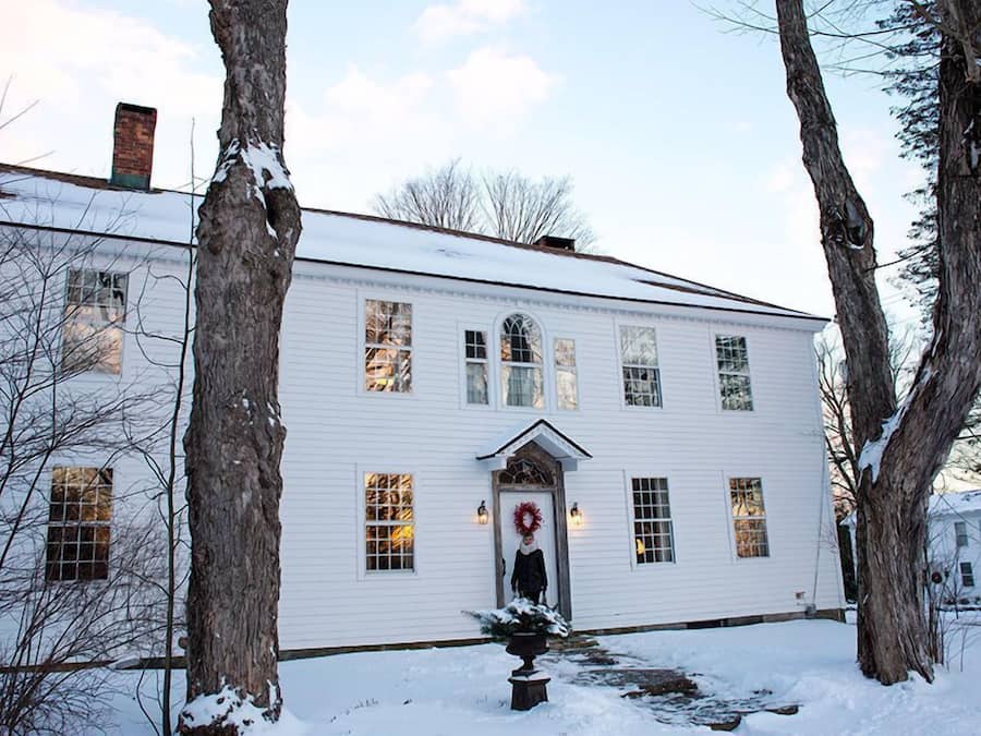 A white two-story house with a front door, windows, and a chimney.