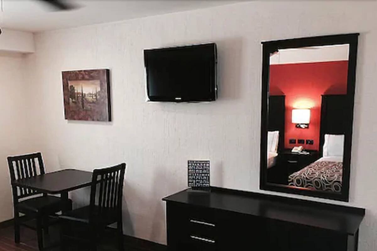 Une chambre d’hôtel comprenant un lit, un téléviseur fixé au mur, un bureau avec une chaise et une petite table.
