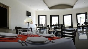 Een eetgedeelte met een hoge plafond, grote ramen en een modern interieur.