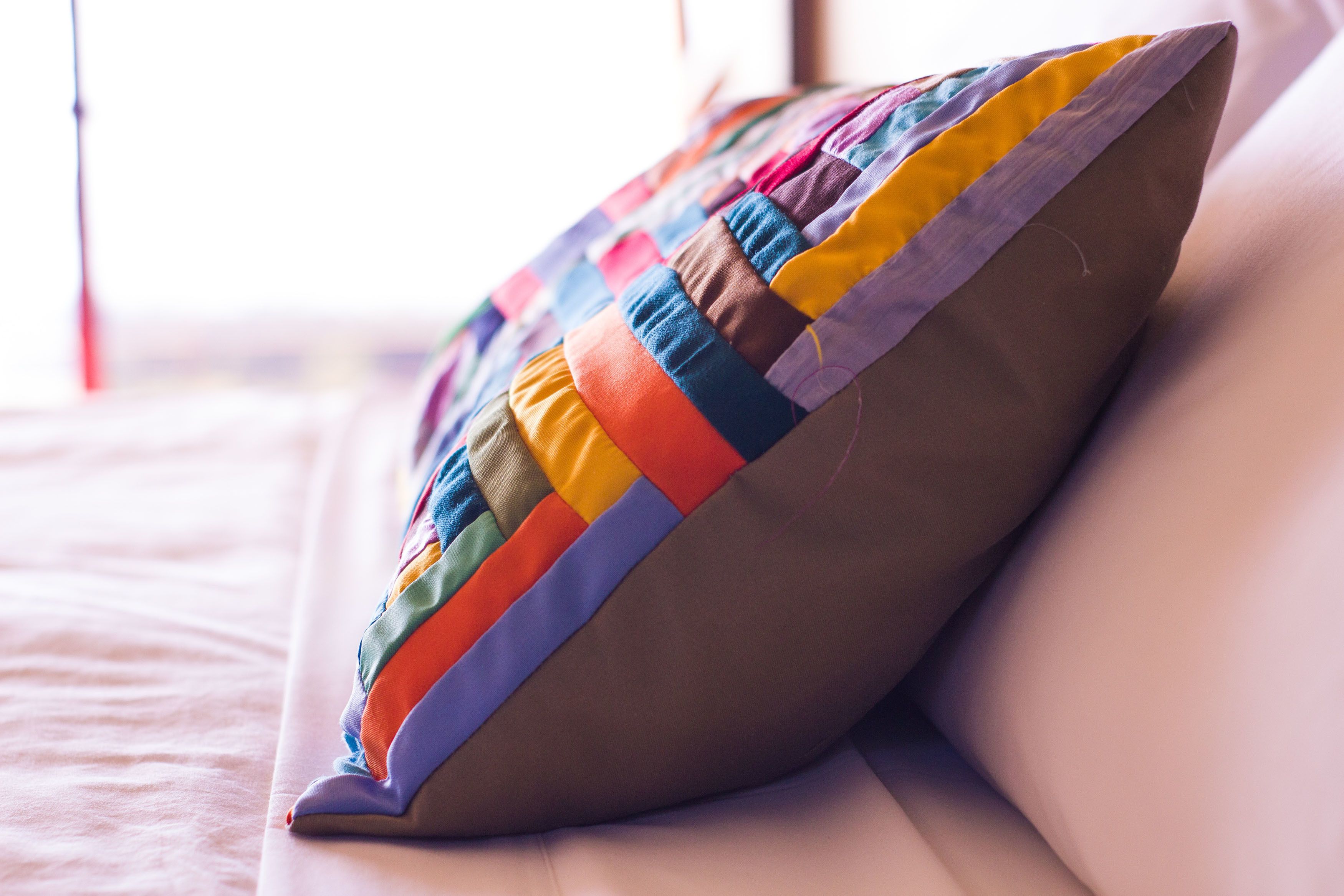 A pillow with a colorful patchwork design on a bed.